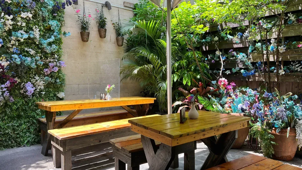 Loreley's outdoor beer garden: picnic tables under palms and a flower wall