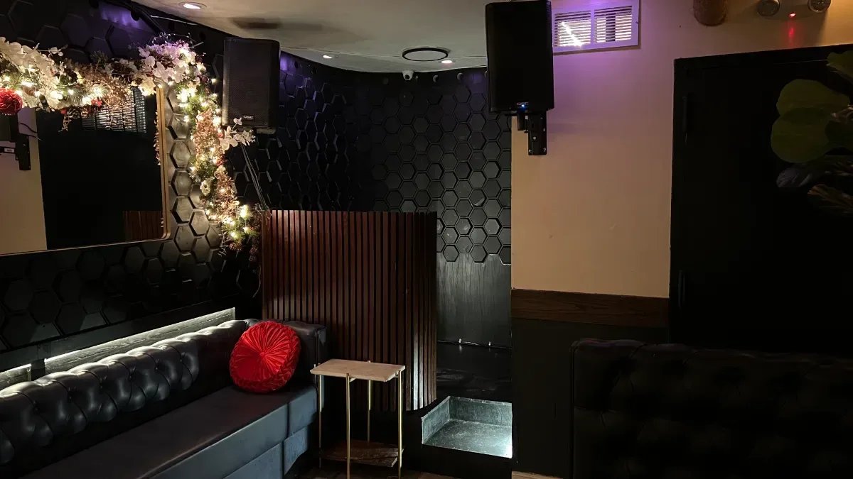 A corner of the party room at Loreley Beer Garden, with a tufted banquette, a red cushion and lights strung around a mirror